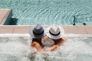 dos personas en una piscina con sombrero en Das Ronacher Therme & Spa Resort, en Bad Kleinkirchheim