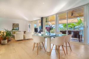 a dining room with a glass table and white chairs at Penthouse La Victoria in Cielo de Bonaire 