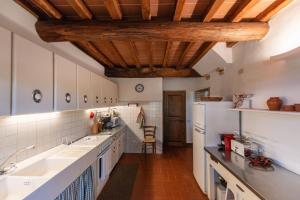 シエナにあるCapannaの白いカウンターと木製の天井が備わるキッチン