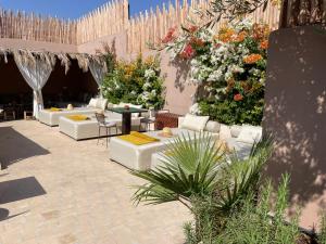 een patio met witte banken, tafels en bloemen bij RIAD SHANAM Location Privative in Marrakesh