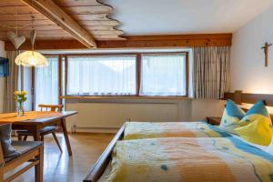 sypialnia z łóżkiem, stołem i oknami w obiekcie Ferienwohnung Angelika w mieście St. Gallenkirch