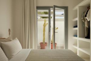 a bedroom with a bed and a cactus next to a window at Isychos House in Mikri Vigla