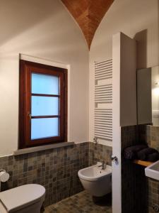 ein Bad mit einem Waschbecken, einem WC und einem Fenster in der Unterkunft Fornace del Conte in Abbadia di Montepulciano