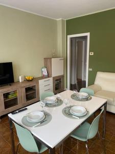 una mesa blanca con sillas, platos y copas de vino en Casa Vacanze Dell'Oro (Appartamento & Garage), en Domodossola