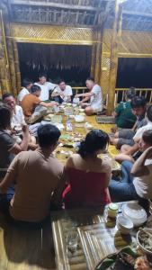 un grupo de personas sentadas alrededor de una mesa larga en Lakeview Homestay Vu Linh, en Yen Bai