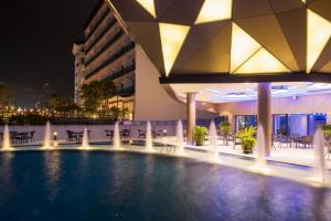 a hotel swimming pool at night with tables and chairs at Rodina Beach Hotel in Jomtien Beach