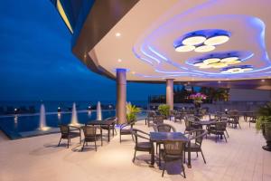 een restaurant op het dak van een gebouw met tafels en stoelen bij Rodina Beach Hotel in Jomtien Beach
