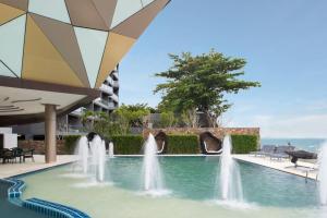 a pool with water fountains in front of a building at Rodina Beach Hotel in Jomtien Beach