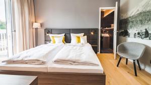 a bedroom with a large white bed and a chair at Hotel Garni Maximilian in Dingolfing