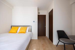 a bedroom with a bed with yellow pillows and a chair at Crest Court Kagurazaka in Tokyo