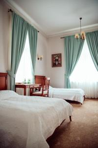 a bedroom with two beds with blue curtains and a table at Zespół Pałacowo-Parkowy w Ostromecku in Ostromecko