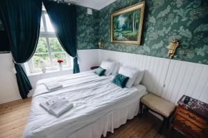 Un dormitorio con una gran cama blanca con papel pintado verde en Mjällbyhus Pensionat & Stugby en Sölvesborg