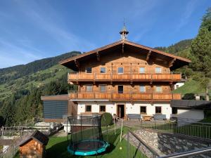 - un grand bâtiment en bois avec une aire de jeux devant dans l'établissement Apartment Oberguggenhausen, à Brixen im Thale