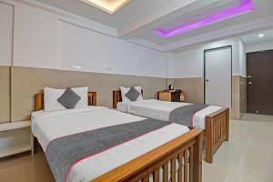 two beds in a hotel room with a purple light at Super Townhouse 1266 Empire Executive in Pune
