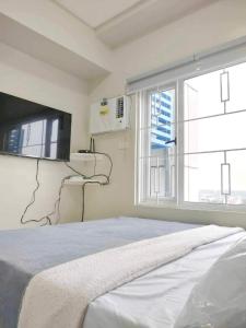 a bedroom with a bed and a tv and a window at Best Condo Studio within Limketkai Center in Cagayan de Oro