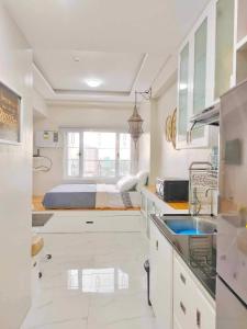 eine Küche mit weißen Schränken und einem Bett im Hintergrund in der Unterkunft Best Condo Studio within Limketkai Center in Cagayan de Oro