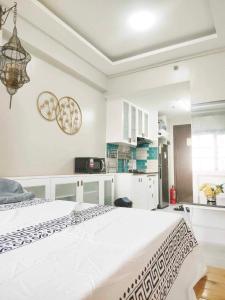 a bedroom with a white bed and a kitchen at Best Condo Studio within Limketkai Center in Cagayan de Oro
