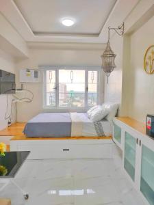 a bedroom with a bed with a desk and a window at Best Condo Studio within Limketkai Center in Cagayan de Oro