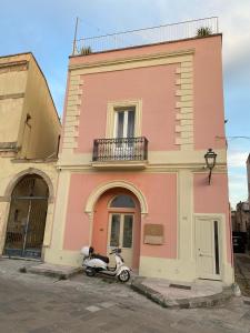 a scooter parked in front of a pink building at Lucente Rooms & Suites in Ugento