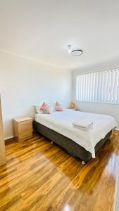 a bedroom with a bed and a wooden floor at Quiet family Townhouse in Wollongong CBD in Wollongong