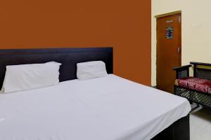 a white bed in a room with an orange wall at Suman Niwas in Lucknow