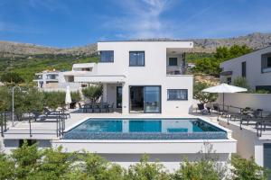 une villa avec une piscine en face d'une maison dans l'établissement NEW! Stylish Villa Olea with heated pool and panoramic sea views, à Podstrana