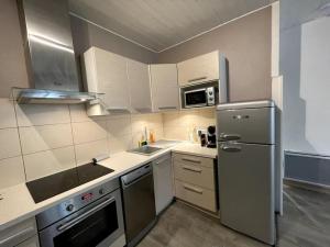Una cocina con refrigerador de acero inoxidable y microondas. en Le Cocon Savoyard, en Albertville 4 fotos más