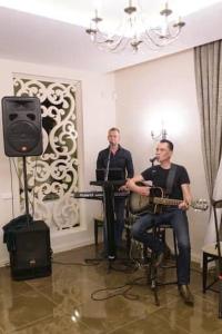 two men playing instruments in a room with a microphone at Villa Orchidea in Šakiai