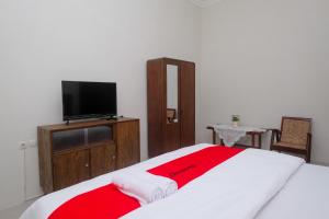 a bedroom with a bed with a red and white blanket at RedDoorz Syariah near Stasiun Klaten in Klaten