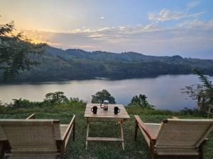 een tafel en 2 stoelen met uitzicht op een meer bij Baranko Villa in Fort Portal