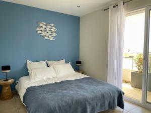 a blue bedroom with a bed with a blue wall at Spacieux apt à proximité du port: clim et parking in Bandol