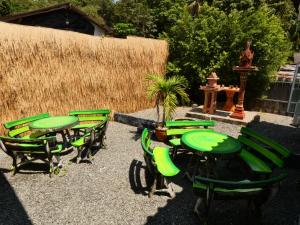 a group of green tables and chairs in a yard at Lemon Guesthouse in Ko Chang