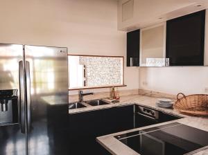 a kitchen with black cabinets and a stainless steel refrigerator at Hotel et Spa Le Lion d'Or in Pont-lʼÉvêque