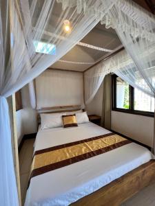 Ursula Beach Resort في إل نيدو: سرير في غرفة بها مظلة