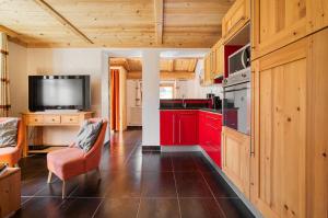 cocina con armarios rojos y TV de pantalla plana en Appartement Petite Charline, en Tignes