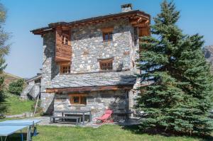 un edificio de piedra con una mesa de picnic y un árbol en Appartement Petite Charline, en Tignes
