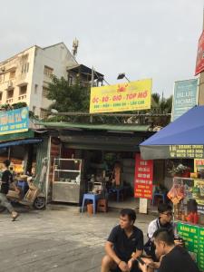 a group of people sitting in front of a market at 3BT home in Hanoi