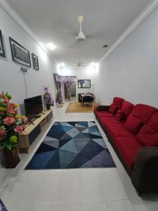 a living room with a red couch and a table at Zara Homestay @ Kok Lanas in Ketereh