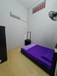 sypialnia z fioletowym łóżkiem w białym pokoju w obiekcie Zara Homestay @ Kok Lanas w mieście Ketereh
