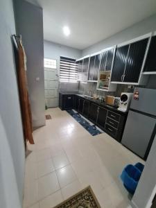 a kitchen with black cabinets and a white tile floor at Zara Homestay @ Kok Lanas in Ketereh