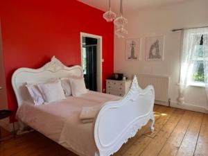 a bedroom with a white bed and red walls at Walltree House in Brackley