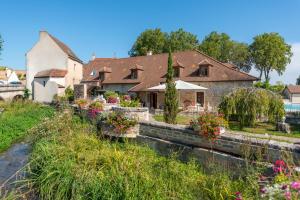 Hotel Le Clos De La Vouge في Vougeot: منزل به زهور على جانب النهر