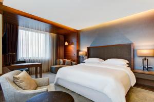 a hotel room with a large bed and a chair at Sheraton Grand Samsun Hotel in Samsun