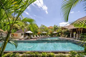 a pool at a resort with chairs and umbrellas at Kailash Suites by Pramana Villas in Ubud