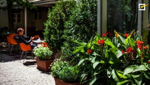 a man sitting at a table with flowers and plants at Schlossquadrat Apartement 14 A in Vienna