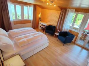 a bedroom with a large white bed and a desk at Swiss Apartment Thunersee in Einigen