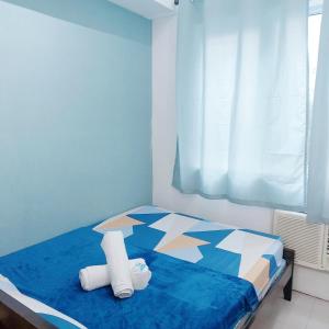 Un dormitorio con una cama azul con toallas. en Sea Residences by Jan & Val Alano, en Manila