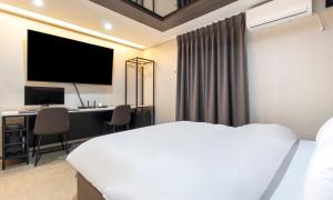 a bedroom with a bed and a desk with a television at Hwaseong Stay13 Hotel in Hwaseong