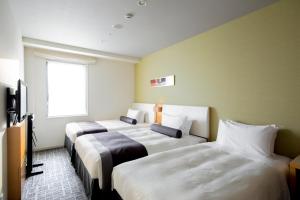 a hotel room with three beds and a window at Tokyu Stay Kamata - Tokyo Haneda in Tokyo