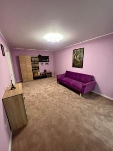un soggiorno con divano viola e tavolo di Apartament Ingrid a Piatra Neamţ